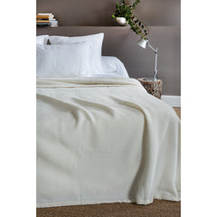 Ecru lamswollen deken op een bed